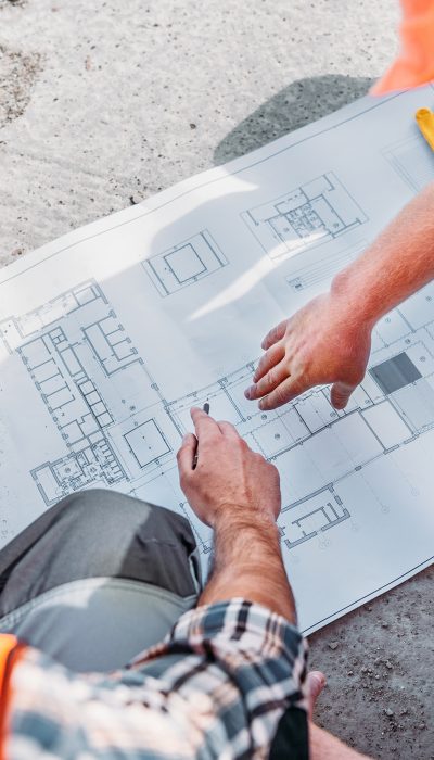 high angle view of builders pointing at blueprint